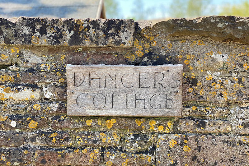 'Dancer's Cottage' house sign on an old wall
