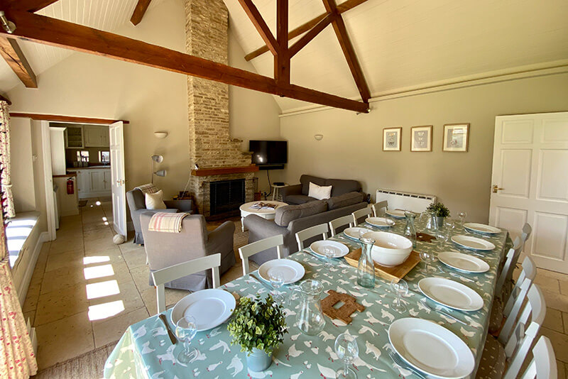 Large dining table set for a meal inside an old cottage with wooden beams