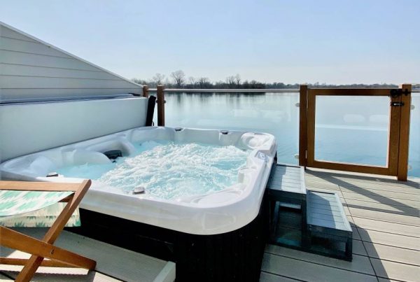 Hot tub on decking next to a lake on a warm day