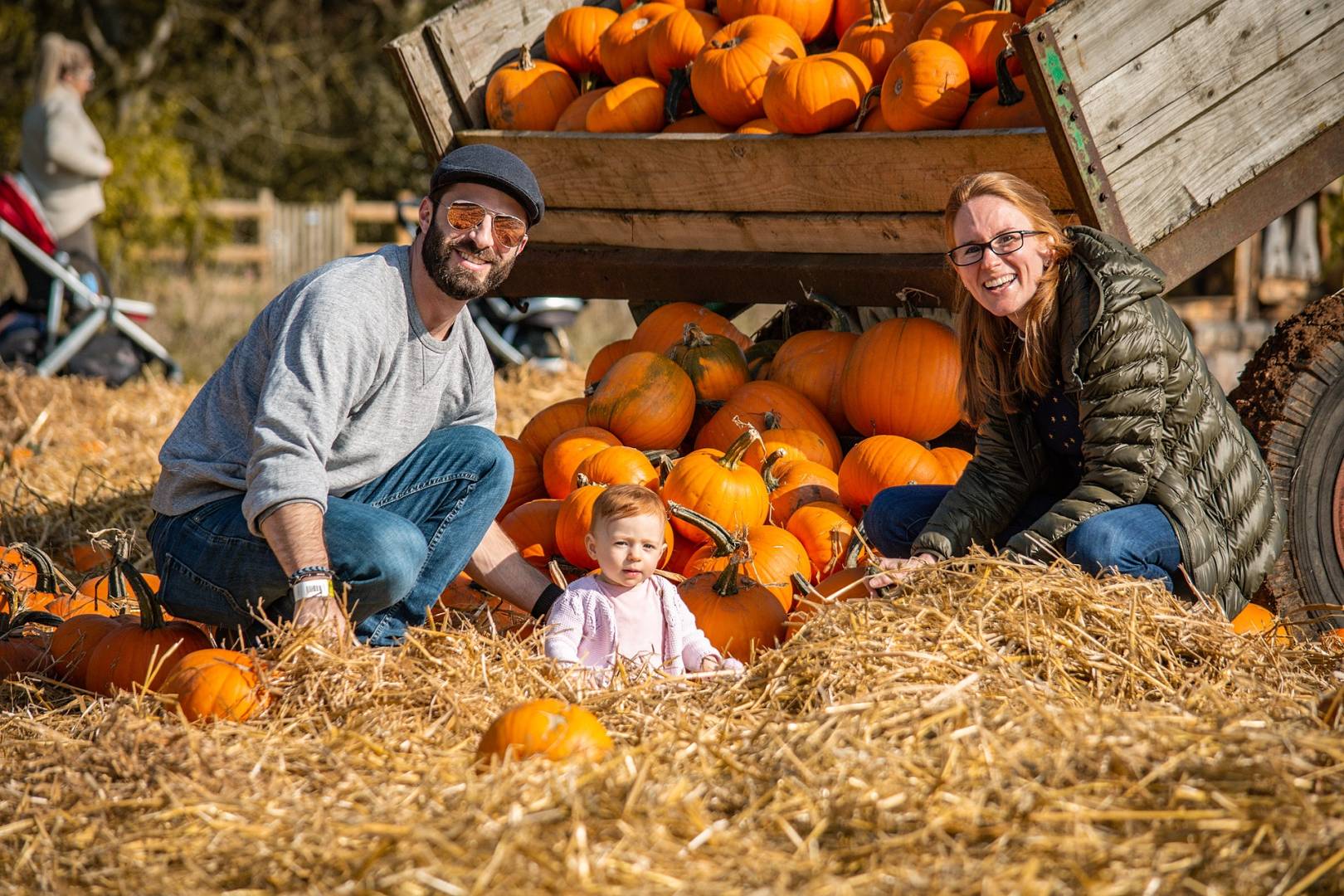 Couple with baby sitting in a pumpkin patch during October half term